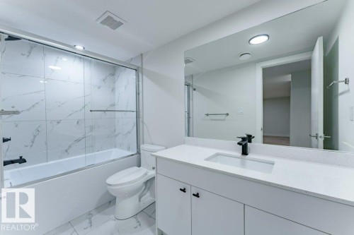 Contemporary bathroom featuring a white vanity with an integrated sink, a dark faucet, and a large wall-mounted mirror - 6920/6922 106 Street, Edmonton, AB - Indoor Photo Showing Bathroom