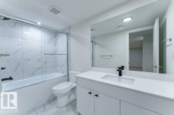 Contemporary bathroom featuring a white vanity with an integrated sink, a dark faucet, and a large wall-mounted mirror - 