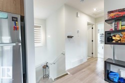 Light wood-finish flooring extending from the hallway, leading to a staircase with a white railing - 