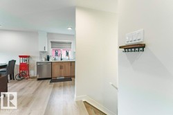 Kitchen with stainless steel appliances, wood-finish lower cabinetry, white upper cabinetry, and a black faucet - 