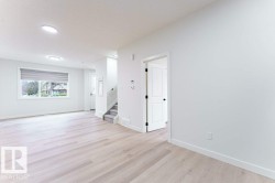 Open concept living area featuring light wood-finish flooring, recessed lighting, and a large window with privacy blinds - 
