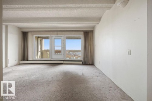 Carpeted interior space with a door leading to an outdoor balcony - 1208 9918 101 Street, Edmonton, AB - Indoor Photo Showing Other Room