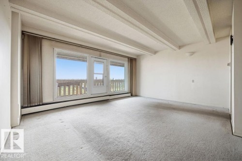 Carpeted interior space featuring a full-length window and glass-paned exterior door - 1208 9918 101 Street, Edmonton, AB - Indoor Photo Showing Other Room