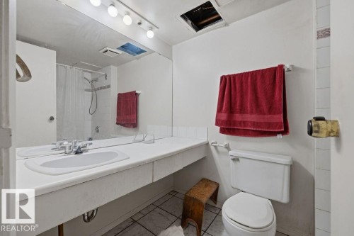 Bathroom featuring a shower-tub combination, vanity with integrated sink, wall-mounted mirror, overhead lighting, and toilet - 1208 9918 101 Street, Edmonton, AB - Indoor Photo Showing Bathroom