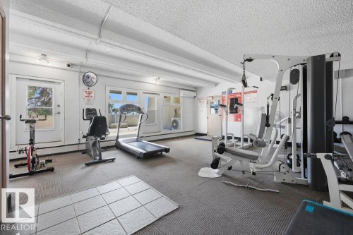 Dedicated fitness space featuring an exercise bike, recumbent bike, treadmill, and multi-station weight machine - 1208 9918 101 Street, Edmonton, AB - Indoor Photo Showing Gym Room