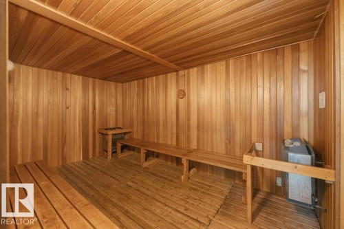 Sauna room featuring full wood paneling, wood slatted benches, and a built-in sauna heater - 1208 9918 101 Street, Edmonton, AB - Indoor Photo Showing Other Room