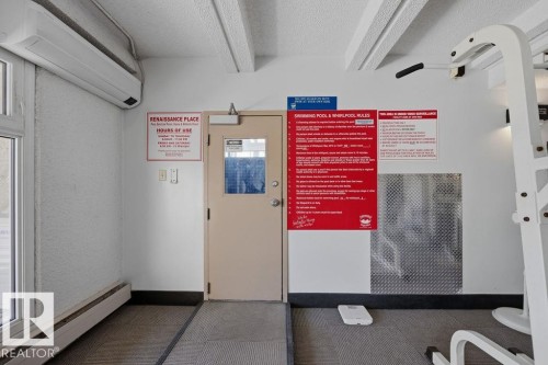 Interior space featuring a split-system air conditioning unit, light-colored walls, a commercial-style door with a window, and a textured ceiling - 1208 9918 101 Street, Edmonton, AB - Indoor Photo Showing Basement