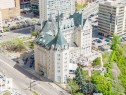 Historic building featuring stone exterior, steeply pitched green roofs, multiple turreted towers, surrounding green landscaping, and outdoor patio spaces - 1208 9918 101 Street, Edmonton, AB  - Outdoor 