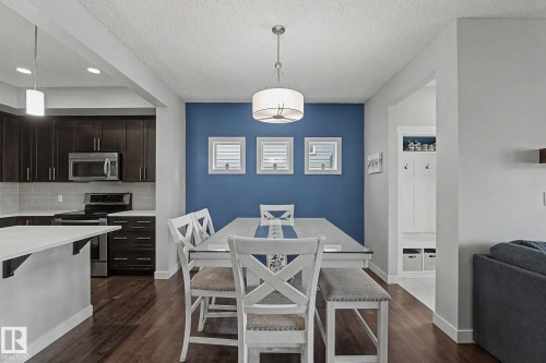 Open-concept dining area featuring a distinct accent wall and wood-finish flooring - 18144 76 Street, Edmonton, AB - Indoor
