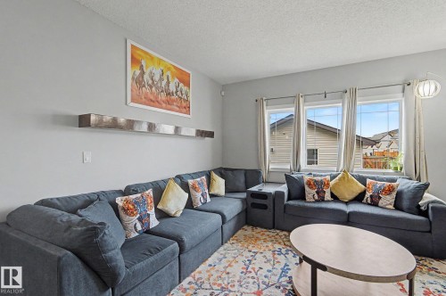 Living area featuring light gray walls, multiple large windows with light-colored drapes, and a textured ceiling - 18144 76 Street, Edmonton, AB - Indoor Photo Showing Living Room