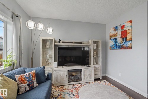 Integrated entertainment center with an electric fireplace, display cabinetry, and dark wood-finish flooring - 18144 76 Street, Edmonton, AB - Indoor Photo Showing Living Room