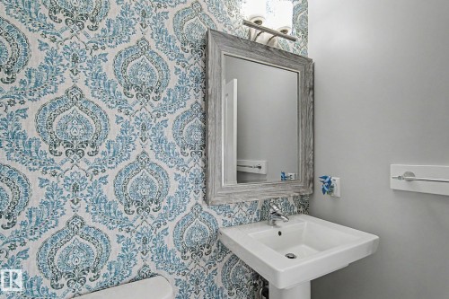 Pedestal sink with chrome faucet, framed mirror, and decorative wall sconce - 18144 76 Street, Edmonton, AB - Indoor Photo Showing Bathroom