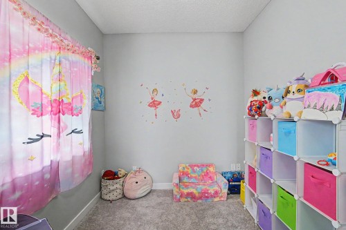 Carpeted room with light grey walls, a window dressed with pink unicorn-themed curtains, and white baseboards - 18144 76 Street, Edmonton, AB - Indoor
