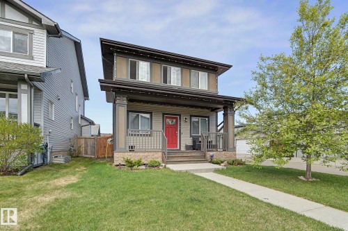 Modern-style home featuring a prominent red entry door, covered porch with columns, and a concrete walkway - 18144 76 Street, Edmonton, AB - Outdoor With Deck Patio Veranda
