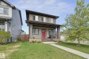 Modern-style home featuring a prominent red entry door, covered porch with columns, and a concrete walkway - 18144 76 Street, Edmonton, AB  - Outdoor With Deck Patio Veranda 