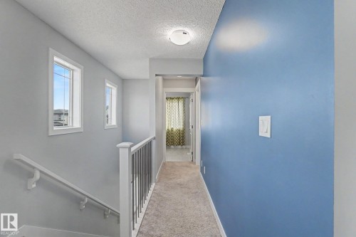 Upper-level landing featuring light gray walls, a contrasting blue accent wall, and textured carpeting - 18144 76 Street, Edmonton, AB - Indoor Photo Showing Other Room