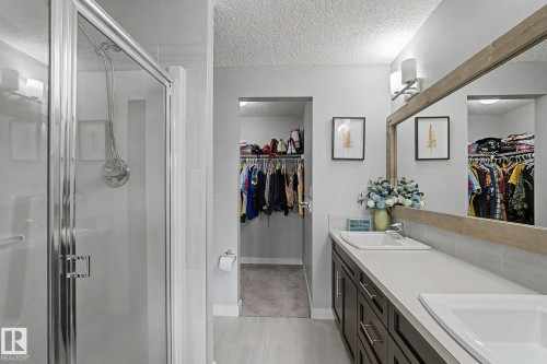 Contemporary bathroom with a glass-enclosed shower, dual vanity, and wood-finish mirror - 18144 76 Street, Edmonton, AB - Indoor Photo Showing Bathroom
