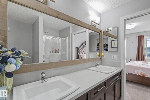 Double vanity featuring white rectangular sinks, chrome faucets, a light-colored countertop, and dark wood-finish cabinetry - 18144 76 Street, Edmonton, AB - Indoor Photo Showing Bathroom