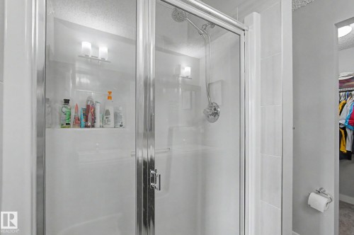 Glass-enclosed shower with a sliding door, featuring a built-in shower niche, chrome fixtures, and white tile surround - 18144 76 Street, Edmonton, AB - Indoor Photo Showing Bathroom