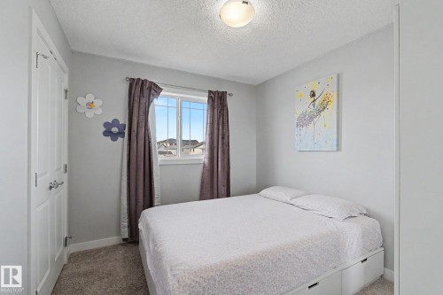 Bedroom featuring neutral wall paint, carpet flooring, a window with curtains, a ceiling-mounted light fixture, and a white paneled door - 18144 76 Street, Edmonton, AB - Indoor Photo Showing Bedroom
