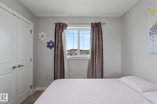 Brightly lit room featuring a double-door closet with polished hardware, a large window, and light-toned wall finishes - 18144 76 Street, Edmonton, AB - Indoor Photo Showing Bedroom