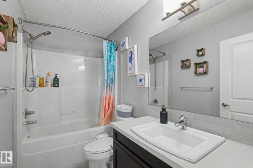 Bathroom featuring a white drop-in sink, chrome fixtures, dark wood-finish vanity, and a full-width mirror - 18144 76 Street, Edmonton, AB - Indoor Photo Showing Bathroom