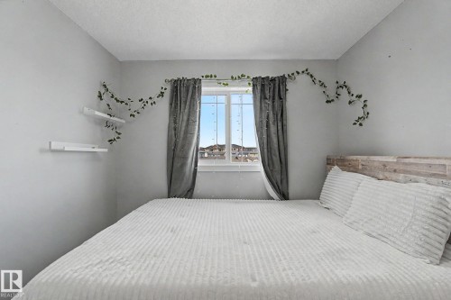 Well-lit room featuring a window with vertical grids and a textured wood-finish headboard - 18144 76 Street, Edmonton, AB - Indoor Photo Showing Bedroom