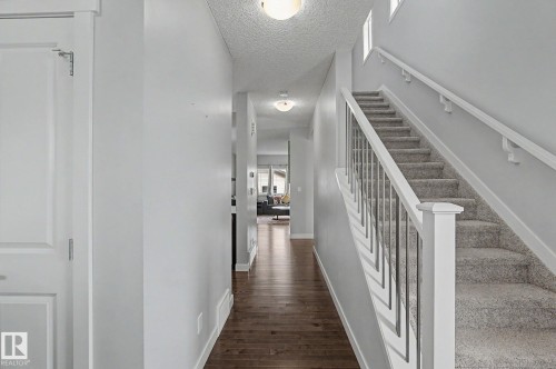 Entryway featuring wood-finish flooring, light grey painted walls, and a carpeted staircase with white railings and metal spindles - 18144 76 Street, Edmonton, AB - Indoor Photo Showing Other Room