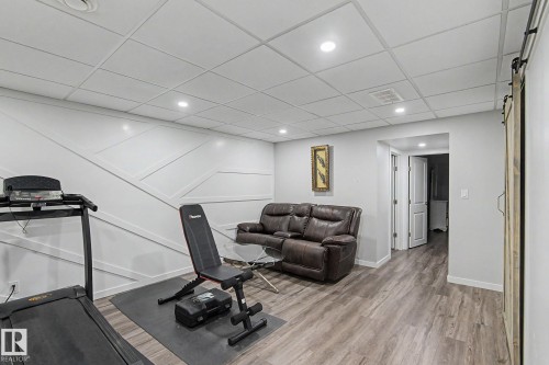 Recreation room featuring wood-finish flooring, a contemporary accent wall, recessed lighting, and a barn door - 18144 76 Street, Edmonton, AB - Indoor