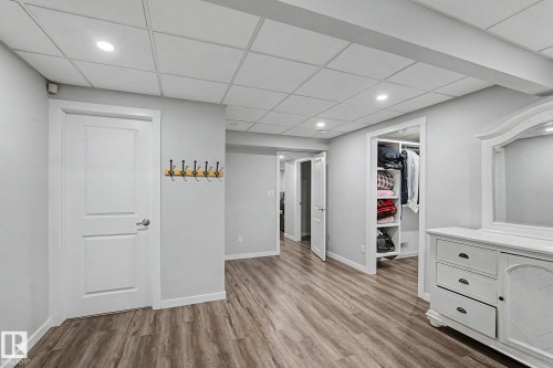 Spacious interior featuring wood-finish flooring, light gray wall paint, and a grid panel ceiling with recessed lighting - 18144 76 Street, Edmonton, AB - Indoor Photo Showing Other Room