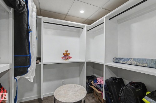Custom closet system with white shelving, integrated hanging rods, recessed lighting, and wood-finish flooring - 18144 76 Street, Edmonton, AB - Indoor With Storage