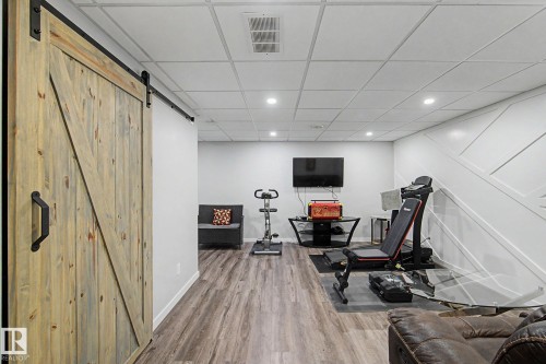 Distressed wood-finish barn door with matte black hardware - 18144 76 Street, Edmonton, AB - Indoor