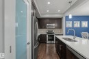 Kitchen featuring dark wood cabinetry, stainless steel appliances, a white countertop island with an undermount sink, and recessed lighting - 18144 76 Street, Edmonton, AB  - Indoor Photo Showing Kitchen With Double Sink With Upgraded Kitchen 