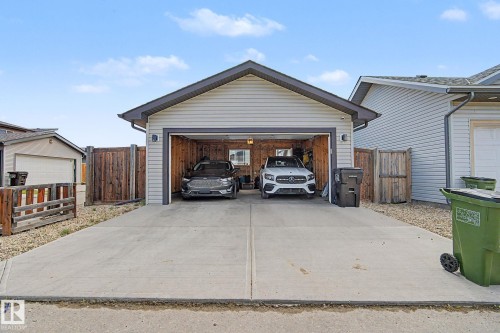 Detached two-car garage with light-toned siding, dark gray roofing, and a concrete driveway - 18144 76 Street, Edmonton, AB - Outdoor With Exterior