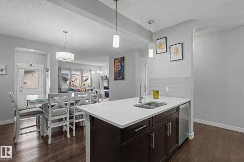 Kitchen island featuring a double-basin sink, stainless steel faucet, and white countertop - 18144 76 Street, Edmonton, AB - Indoor