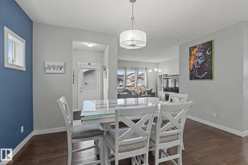 Dining area featuring dark wood-finish flooring, light grey walls, and a contemporary drum pendant light fixture - 18144 76 Street, Edmonton, AB - Indoor Photo Showing Dining Room