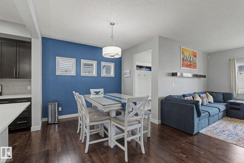 Dining area featuring a contemporary drum pendant light, dark wood-finish flooring, and a blue accent wall with three square window openings - 18144 76 Street, Edmonton, AB - Indoor