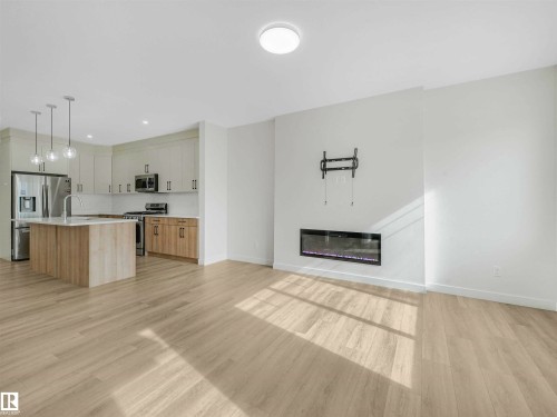 Open-concept living space with light wood-finish flooring - 1518 Siskin Link Link, Edmonton, AB - Indoor With Fireplace