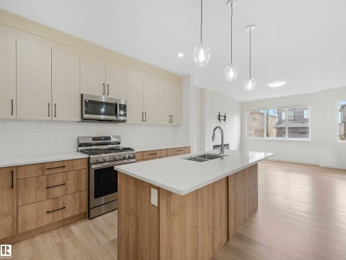 Modern kitchen featuring a central island with an undermount double sink and chrome faucet - 1518 Siskin Link Link, Edmonton, AB - Indoor Photo Showing Kitchen With Double Sink