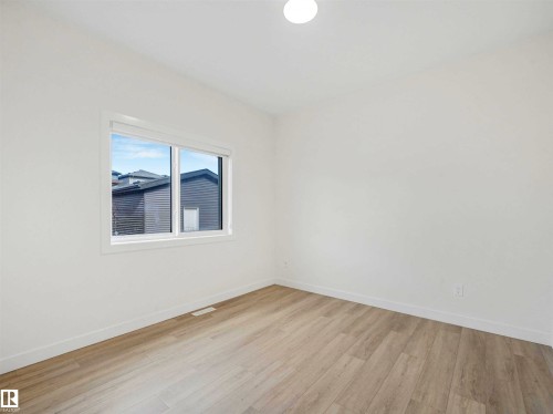 Spacious room featuring light wood-finish flooring, white baseboards, and a single window with white trim - 1518 Siskin Link Link, Edmonton, AB - Indoor Photo Showing Other Room
