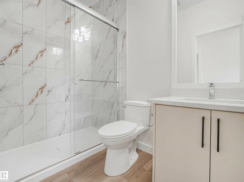 Bathroom featuring a full shower with sliding glass doors, white tiled walls with subtle veining, and a white vanity with a rectangular sink - 1518 Siskin Link Link, Edmonton, AB - Indoor Photo Showing Bathroom
