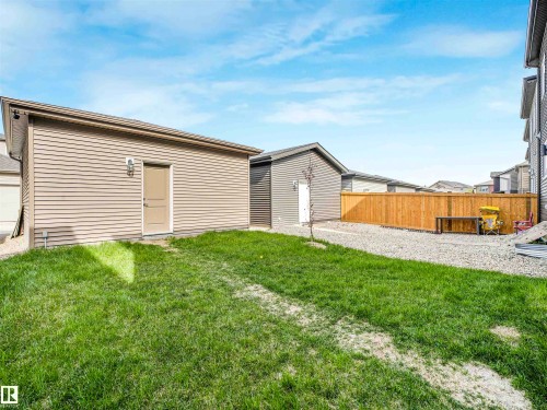 Expansive backyard featuring a manicured lawn, gravel patio, and a wood fence - 1518 Siskin Link Link, Edmonton, AB - Outdoor