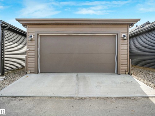 Detached garage with horizontal siding, a single overhead door, and two exterior wall sconces - 1518 Siskin Link Link, Edmonton, AB - Outdoor With Exterior