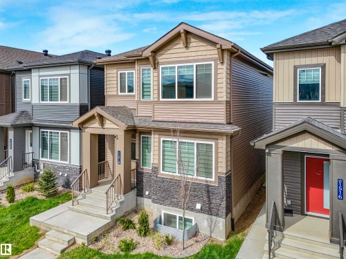 Two-story residential building featuring light brown siding and dark stacked stone accents - 1518 Siskin Link Link, Edmonton, AB - Outdoor With Facade