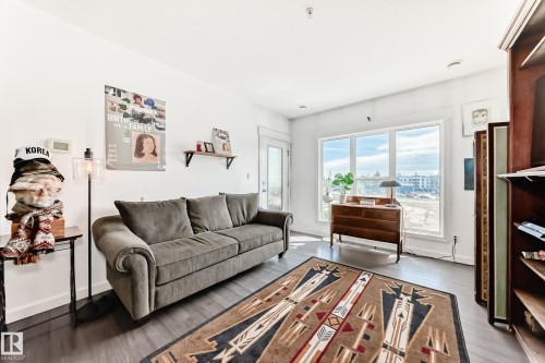 Bright interior space featuring large windows providing natural light, dark wood-finish flooring, white walls, and a built-in shelving unit - 316 10518 113 Street, Edmonton, AB - Indoor Photo Showing Living Room