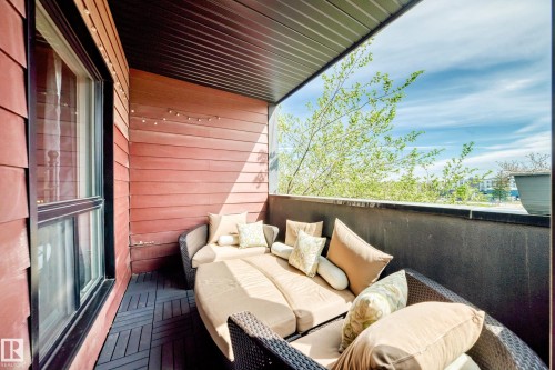 Covered balcony featuring red horizontal siding, dark plank flooring, a dark ceiling, and an exterior window - 316 10518 113 Street, Edmonton, AB - Outdoor With Deck Patio Veranda With Exterior