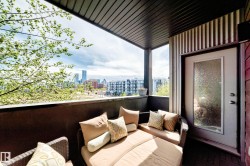 Covered outdoor balcony featuring a dark wood-finish ceiling, urban cityscape scenery, and a frosted glass door - 