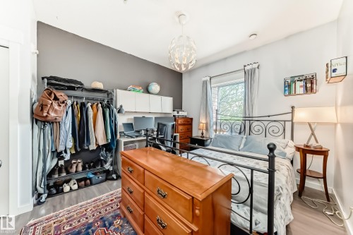 Spacious bedroom featuring wood-finish flooring and a contemporary pendant light fixture - 316 10518 113 Street, Edmonton, AB - Indoor Photo Showing Other Room