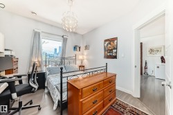 Bedroom featuring wood-finish flooring, a contemporary ceiling light fixture, and a large window - 