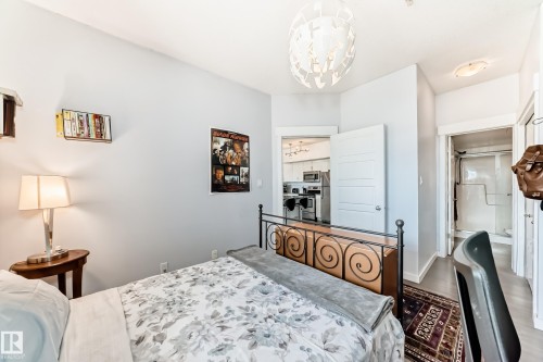 Bedroom featuring a contemporary spherical light fixture, warm gray wall paint, and wood-finish flooring - 316 10518 113 Street, Edmonton, AB - Indoor Photo Showing Bedroom